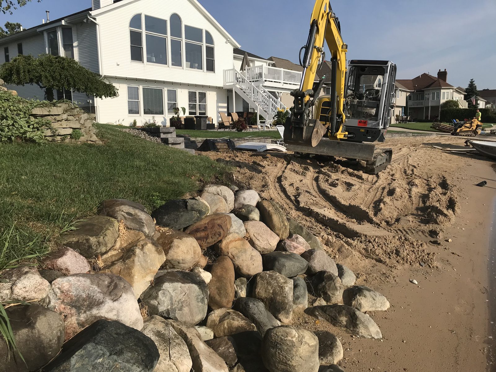 Excavator placing boulders during seawall construction on a Michigan lakefront property